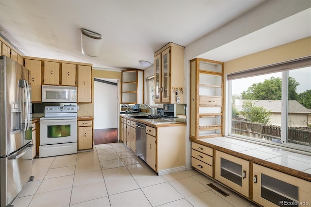 7210 Otis Ct, Arvada, CO 80003 - kitchen with stainless steel appliances, tile countertops, light tile patterned floors, open shelves, and glass insert cabinets