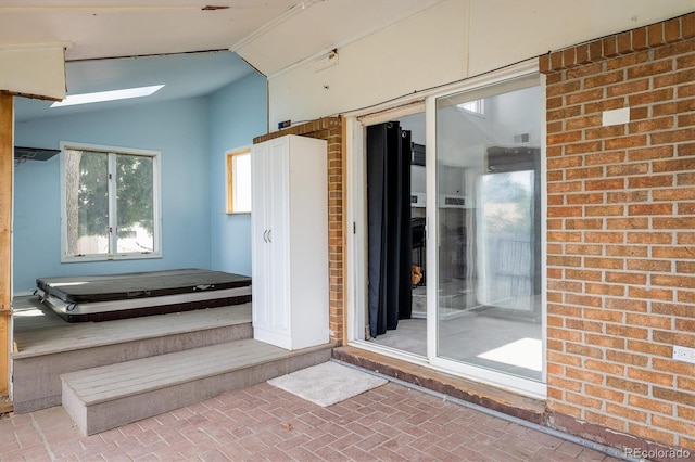 7210 Otis Ct, Arvada, CO 80003 - bathroom featuring brick patterned floors, vaulted ceiling, and a skylight