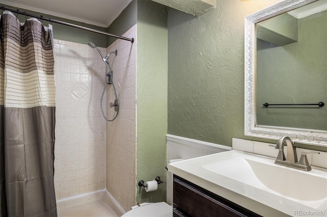7210 Otis Ct, Arvada, CO 80003 - bathroom with a textured wall, vanity, a tile shower, and wainscoting