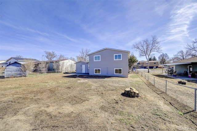 back of property featuring an outdoor fire pit, a shed, an outdoor structure, and a fenced backyard