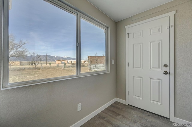 doorway to outside featuring baseboards and dark wood finished floors