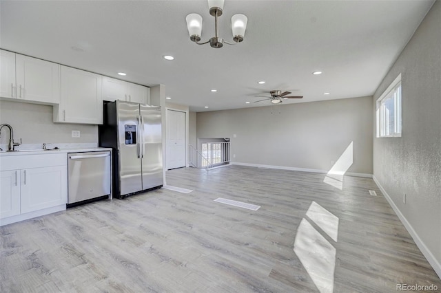 kitchen featuring light wood finished floors, ceiling fan with notable chandelier, plenty of natural light, and appliances with stainless steel finishes