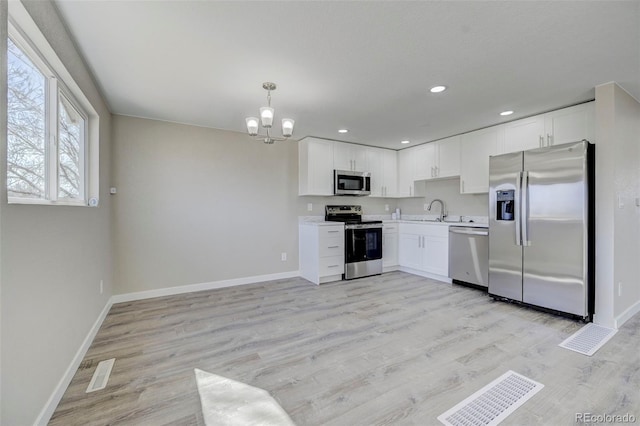 kitchen with an inviting chandelier, light wood-style flooring, light countertops, white cabinets, and appliances with stainless steel finishes