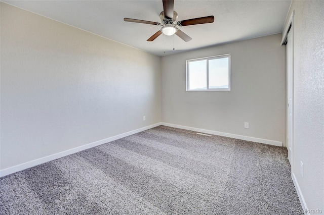 carpeted spare room featuring baseboards and a ceiling fan