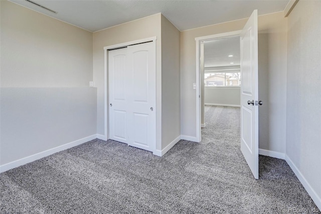 unfurnished bedroom featuring visible vents, baseboards, carpet, and a closet