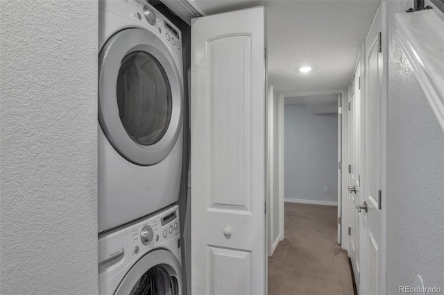 washroom featuring stacked washing maching and dryer and light colored carpet