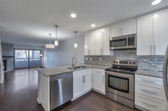 kitchen featuring sink, white cabinetry, kitchen peninsula, stainless steel appliances, and backsplash