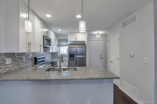 kitchen featuring appliances with stainless steel finishes, sink, white cabinets, kitchen peninsula, and light stone countertops