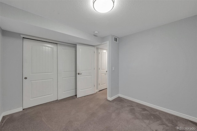 unfurnished bedroom featuring light colored carpet, a textured ceiling, and a closet