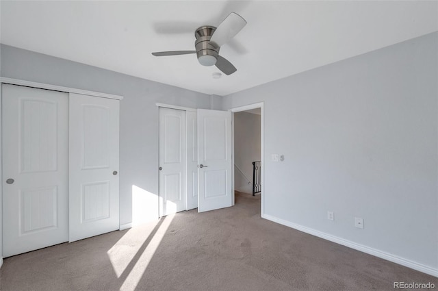 unfurnished bedroom featuring ceiling fan, light colored carpet, and multiple closets