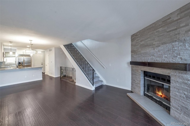 unfurnished living room featuring a stone fireplace and dark hardwood / wood-style flooring