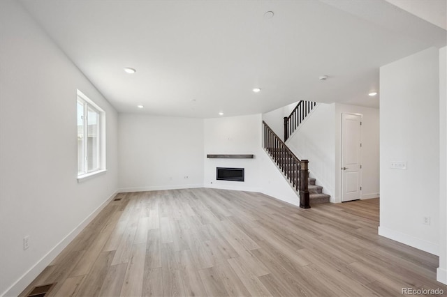 1376 Lumber Ridge Cir N, Erie, CO 80516 - unfurnished living room with a fireplace, light wood finished floors, recessed lighting, stairs, and baseboards