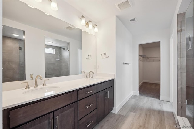 1376 Lumber Ridge Cir N, Erie, CO 80516 - bathroom with a walk in closet, double vanity, tiled shower, wood finished floors, and baseboards