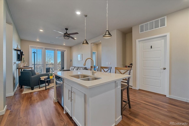 kitchen featuring sink, decorative light fixtures, a center island with sink, a kitchen breakfast bar, and white cabinets