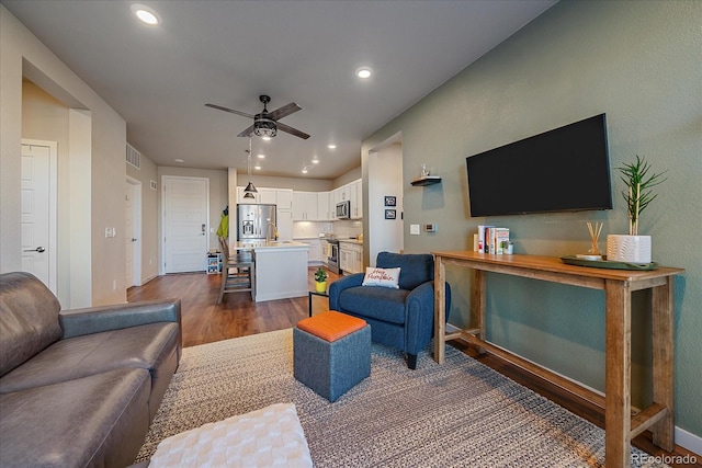 living room featuring ceiling fan and dark hardwood / wood-style floors