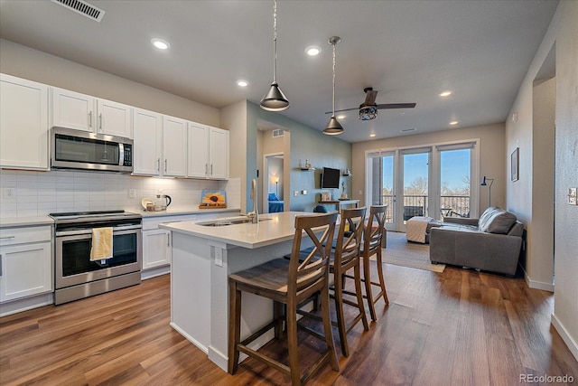 kitchen featuring white cabinetry, appliances with stainless steel finishes, a center island with sink, and a kitchen bar