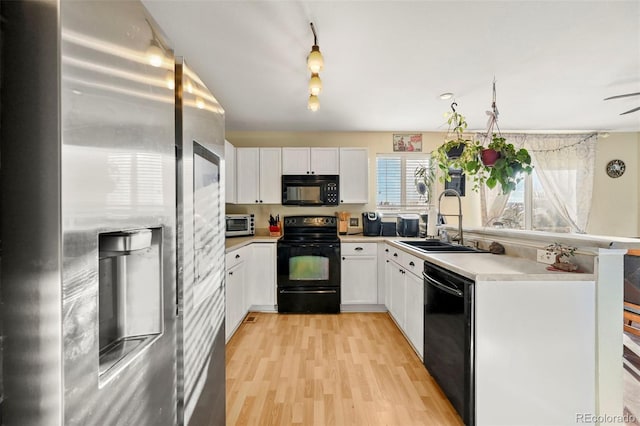 kitchen featuring sink, black appliances, white cabinetry, and light hardwood / wood-style floors