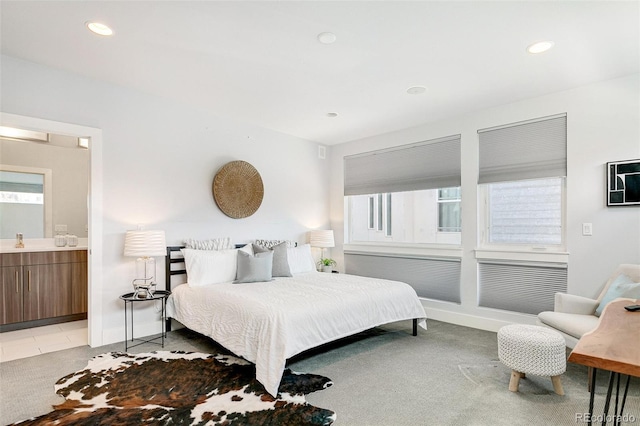 carpeted bedroom featuring ensuite bath and sink