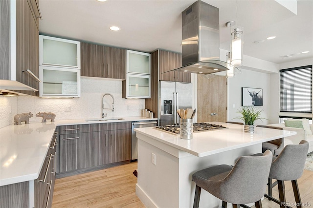 kitchen featuring a kitchen island, appliances with stainless steel finishes, sink, and island range hood