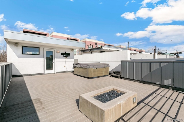 deck with an outdoor fire pit and a hot tub