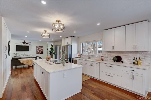 3434 S Race St, Englewood, CO 80113 - kitchen featuring appliances with stainless steel finishes, open floor plan, wood-type flooring, tasteful backsplash, and a center island