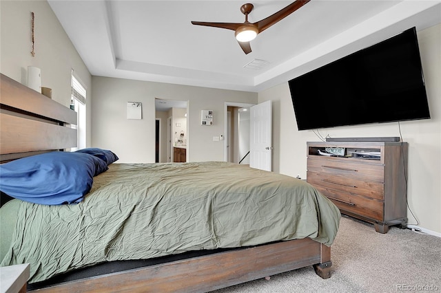 bedroom featuring a tray ceiling, visible vents, a ceiling fan, light carpet, and connected bathroom