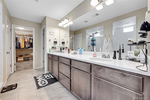 full bathroom with a walk in closet, double vanity, visible vents, a sink, and tile patterned floors