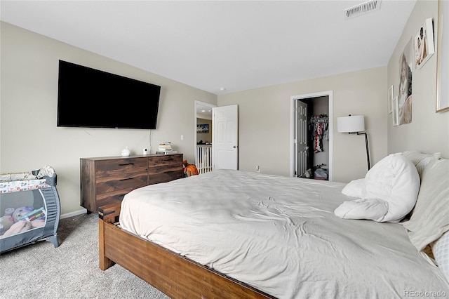 bedroom featuring baseboards, a spacious closet, visible vents, and light colored carpet