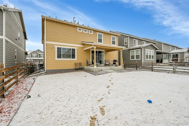 snow covered house with a residential view and fence