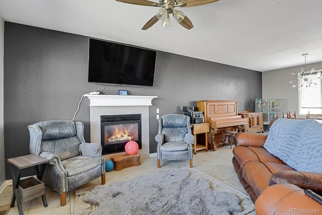 living room with ceiling fan with notable chandelier, light tile patterned floors, and a tiled fireplace