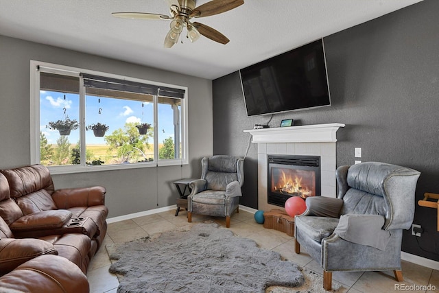 sitting room with a fireplace, light tile patterned floors, and ceiling fan