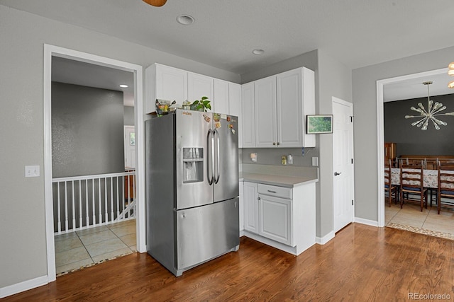 kitchen with pendant lighting, dark hardwood / wood-style floors, stainless steel fridge, and white cabinetry