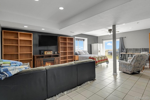 tiled living room featuring a fireplace and ceiling fan