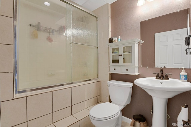 full bathroom featuring combined bath / shower with glass door, toilet, and sink