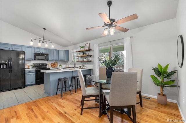 dining room with ceiling fan, lofted ceiling, sink, and light hardwood / wood-style floors