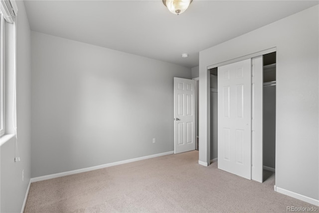 unfurnished bedroom featuring light carpet and a closet