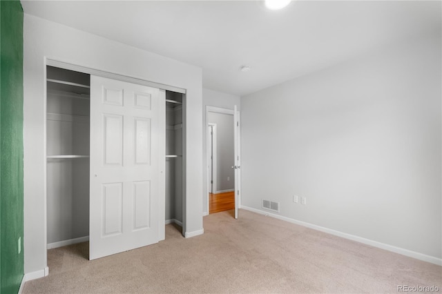 unfurnished bedroom with light carpet and a closet