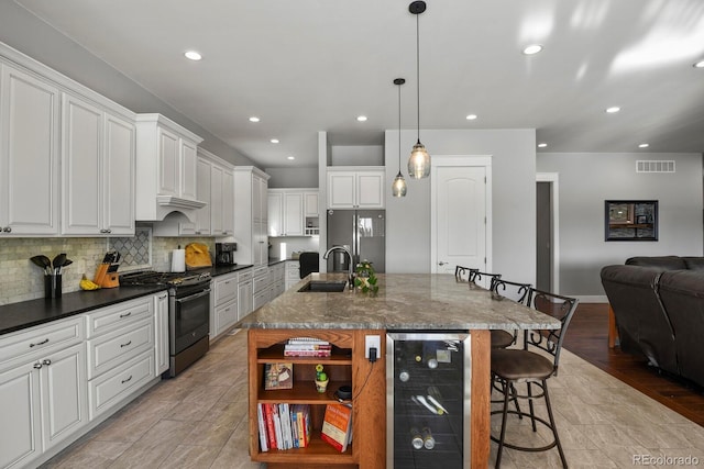 kitchen featuring a large island, hanging light fixtures, beverage cooler, a kitchen bar, and appliances with stainless steel finishes