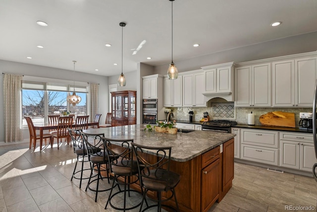 kitchen with decorative light fixtures, black gas stove, white cabinetry, and sink