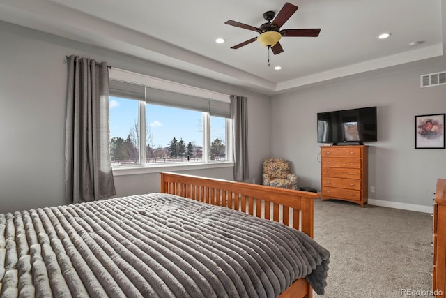 bedroom featuring light colored carpet, a raised ceiling, and ceiling fan