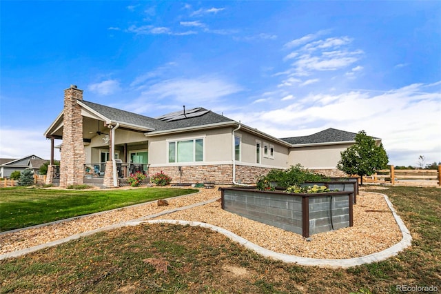 view of side of property with solar panels, ceiling fan, and a lawn