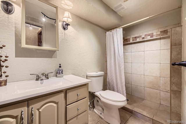 34886 Mohawk Trl, Pine, CO 80470 - full bathroom with a textured wall, toilet, vanity, a tile shower, and tile patterned floors