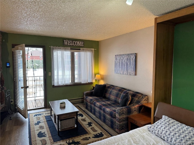 living area featuring a textured ceiling, a baseboard heating unit, and wood finished floors