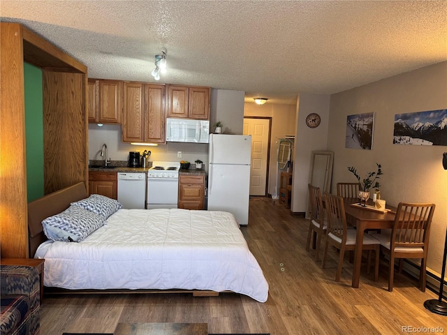 bedroom with freestanding refrigerator, a sink, a textured ceiling, and wood finished floors