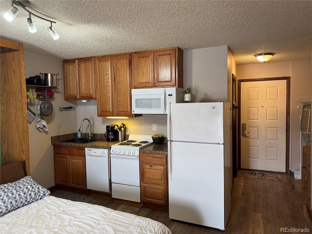 kitchen with brown cabinetry, white appliances, a sink, and dark wood-style flooring