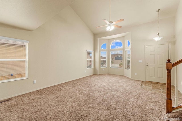 unfurnished room with high vaulted ceiling, carpet, a ceiling fan, baseboards, and stairs