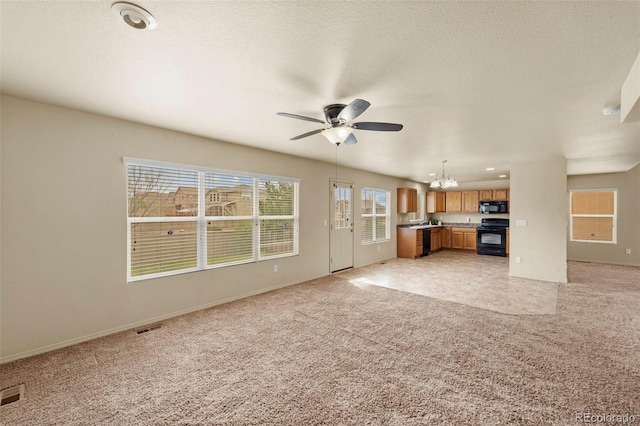 unfurnished living room with light colored carpet, a chandelier, a ceiling fan, and baseboards