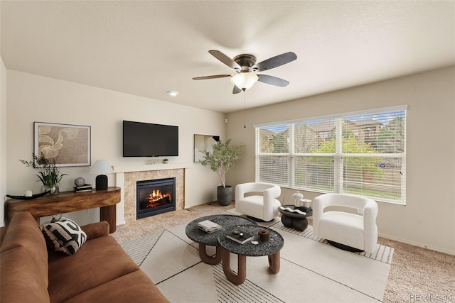 carpeted living area with a ceiling fan, a tile fireplace, and baseboards