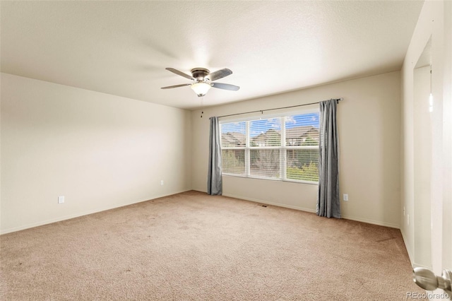 spare room with light colored carpet, a ceiling fan, and baseboards