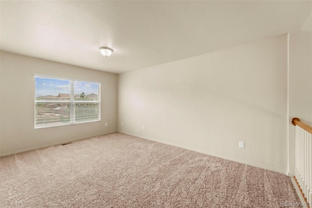 carpeted spare room featuring baseboards